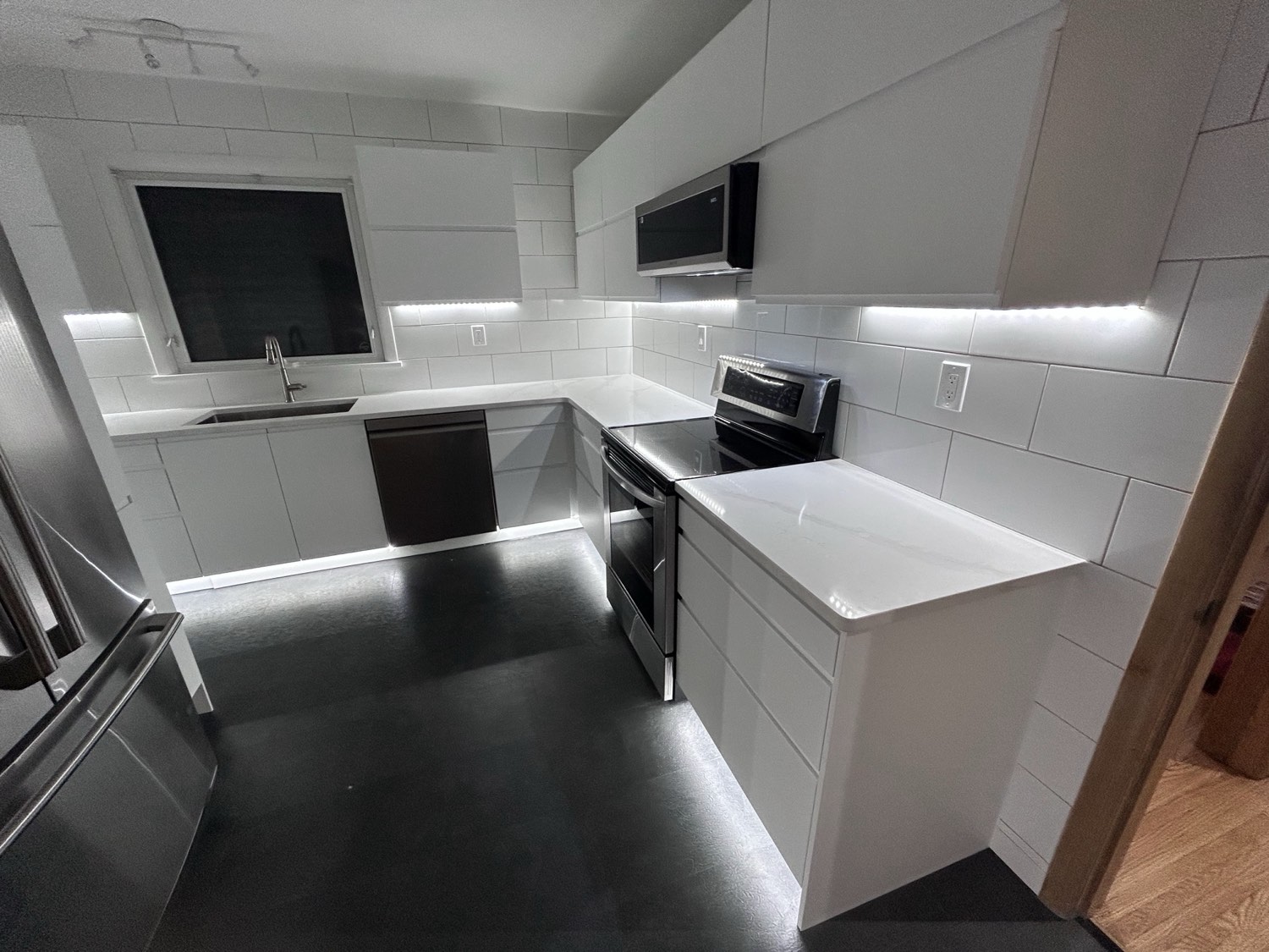 Kitchen with under-cabinet LED lighting over white tile