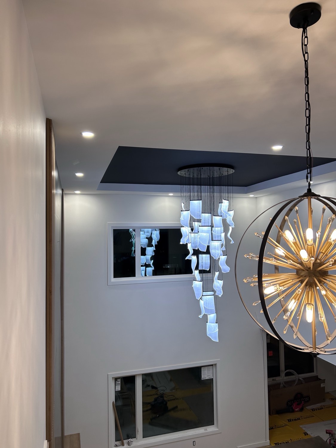 Cascading pendant light and gold sputnik chandelier in a two-storey foyer