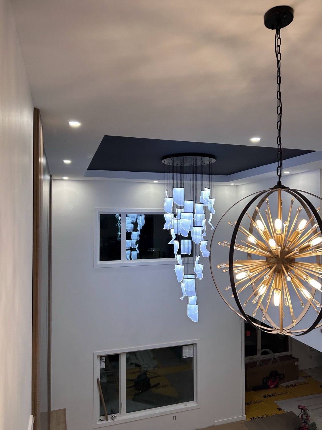 Two-storey foyer with cascade pendant and gold chandelier